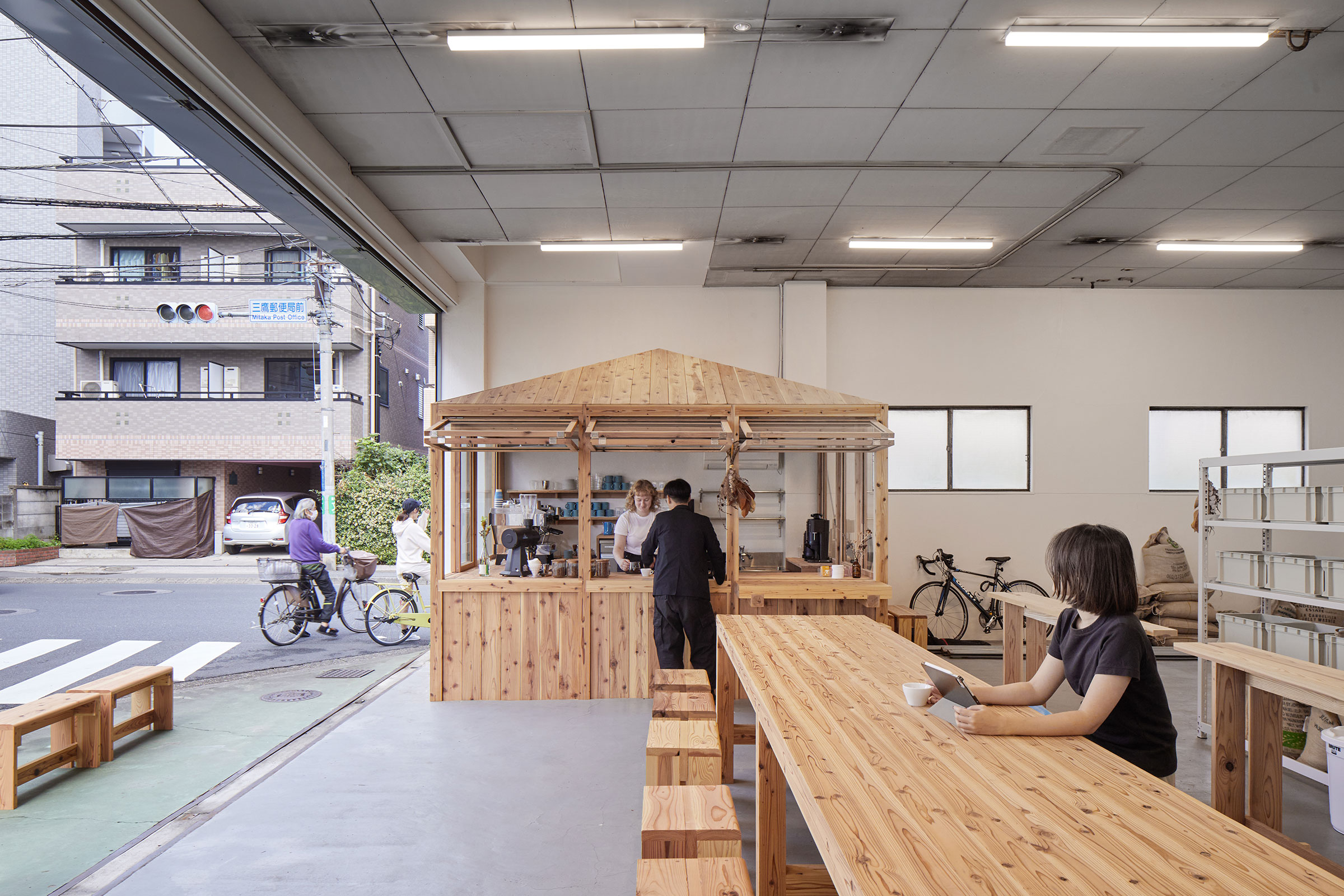 黒崎稜 山本稜 / Spicy Architectsによる、東京の「LIGHT UP COFFEE  三鷹」。旧工場を改修した焙煎所兼カフェ。シャッターの開放で内外が繋がる既存空間を活かし、“ストリートラウンジ”としての店舗を志向。歴史ある焙煎機の活用も意図して訪問客が“焙煎の過程”を見られる平面  ...